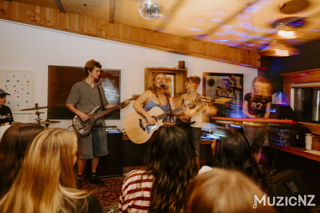 Lead female singer and guitarist, with full band on stage in a bar venue.
